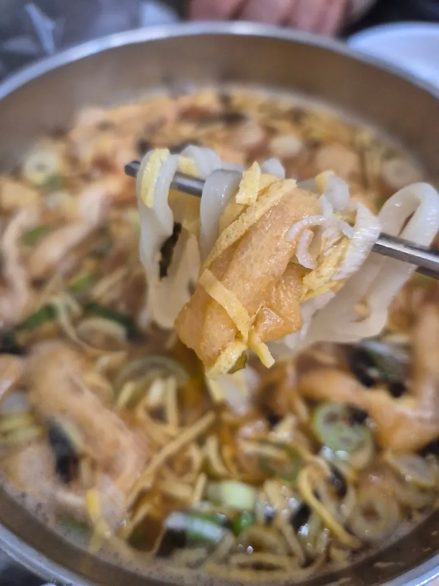 Anchovy kalguksu with seasoning sauce stirred in, deeper in color