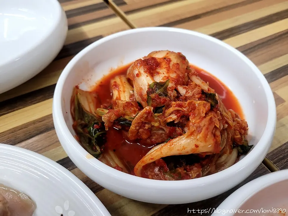 A piece of bossam pork wrapped with radish salad, kimchi, and cabbage