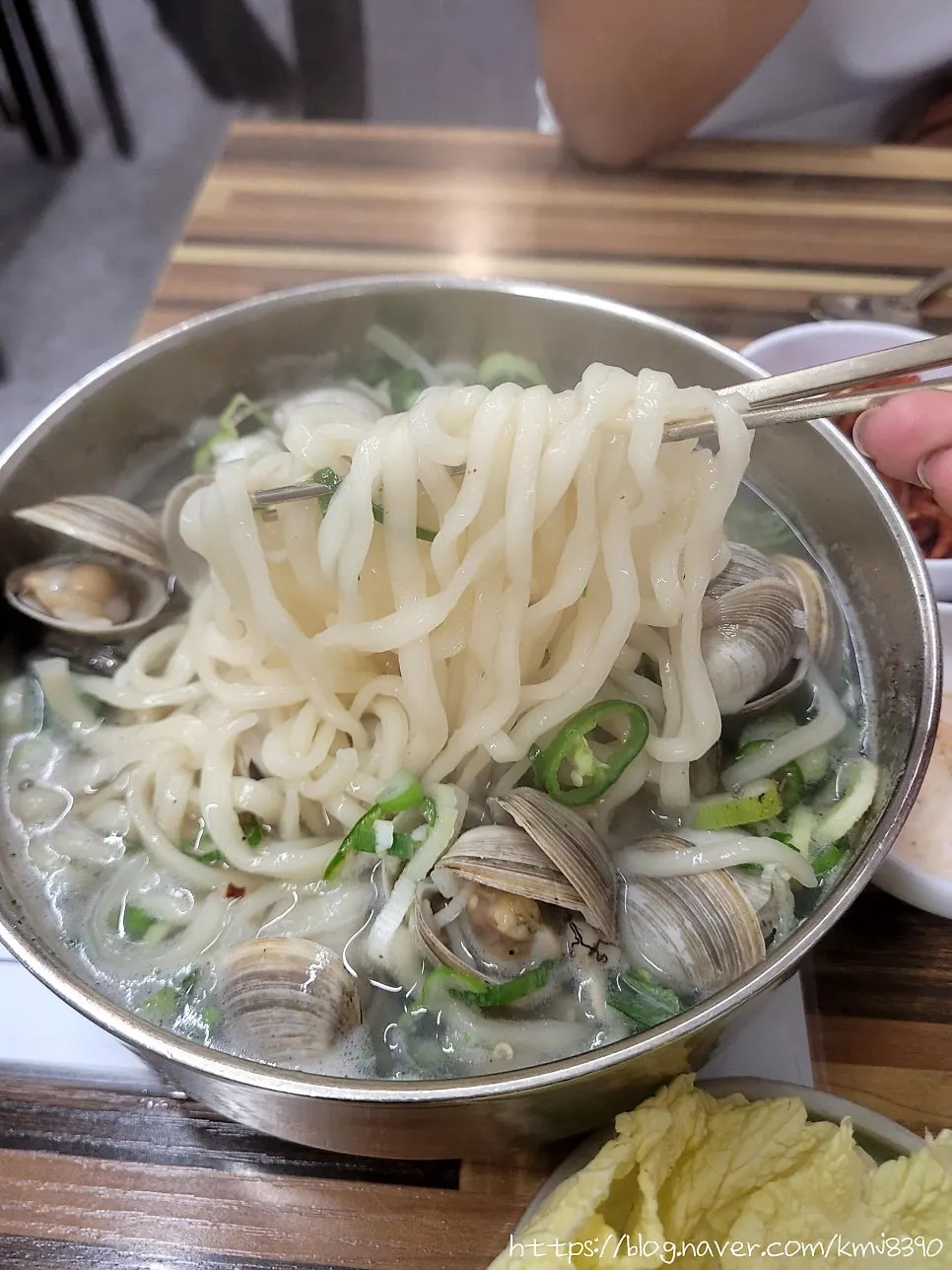Enjoying clam kalguksu broth with a glass of soju
