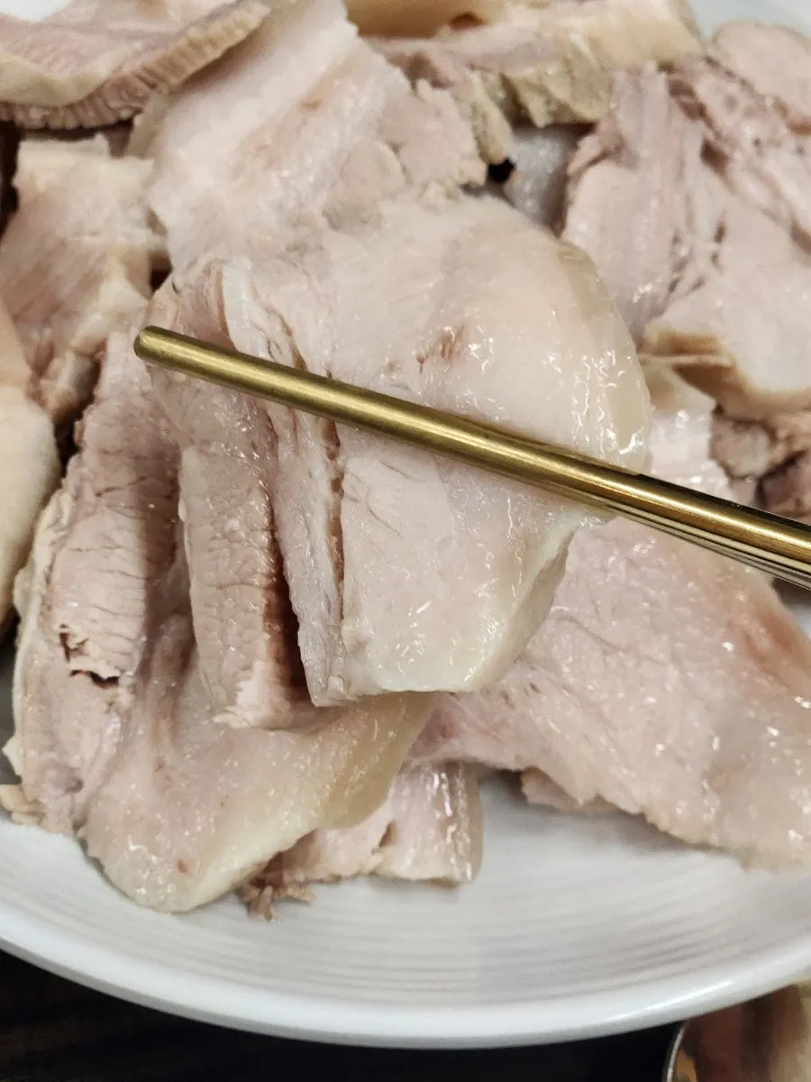 A piece of bossam picked up with chopsticks