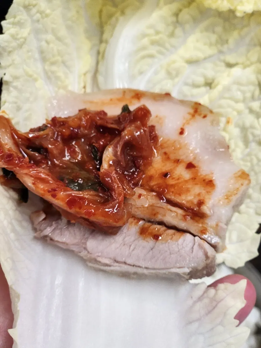 A cabbage wrap loaded with bossam and kimchi