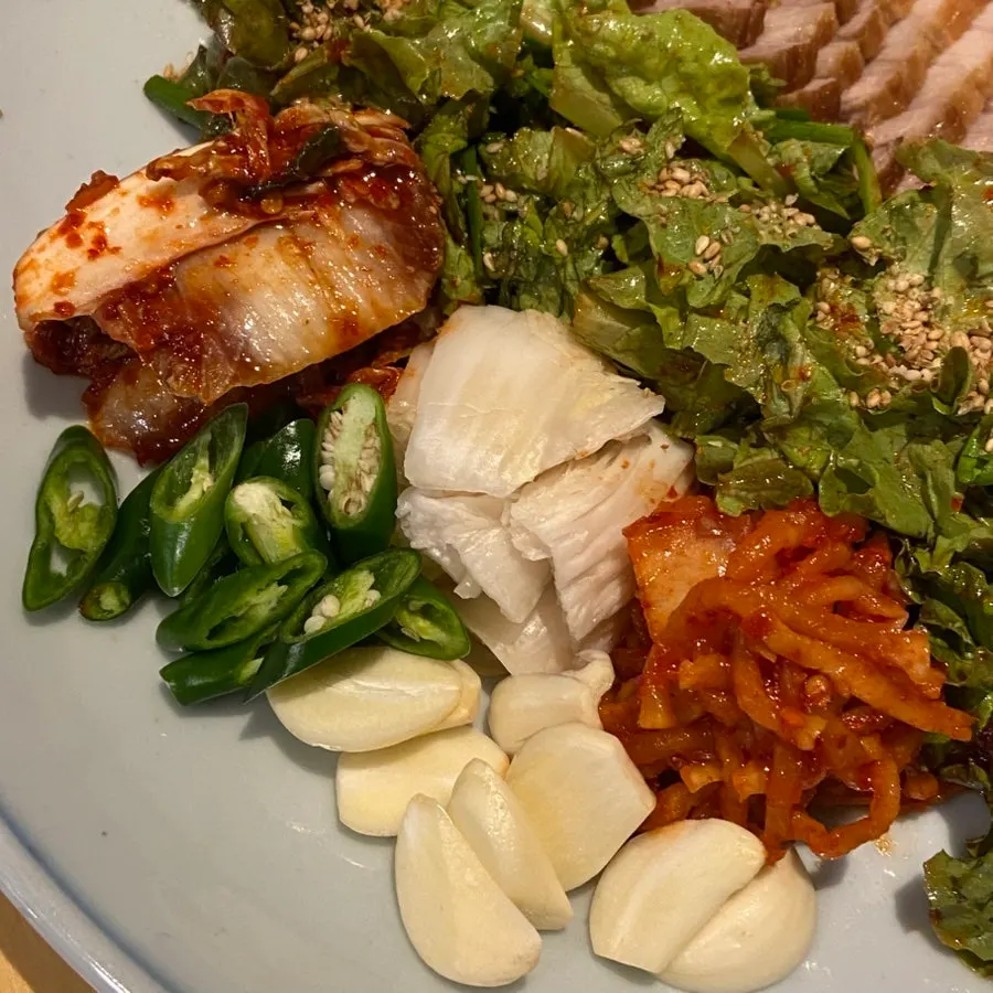Bossam served with vegetables, kimchi, garlic and chili