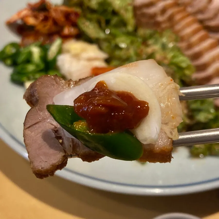 A piece of bossam topped with garlic and chili