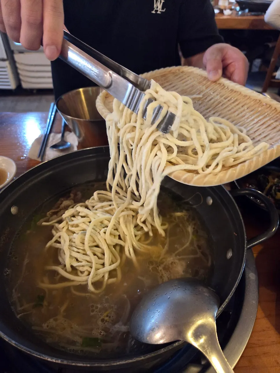 Kalguksu noodles being boiled in the hot pot