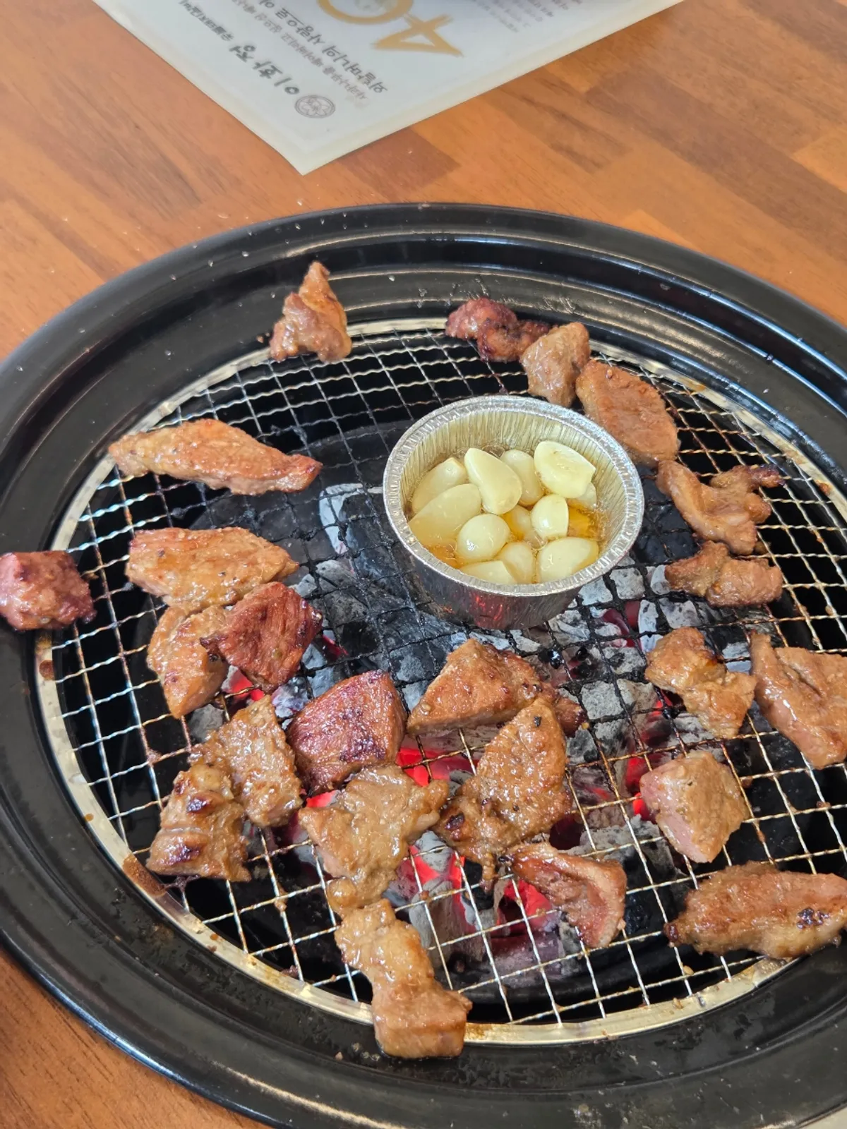 Seasoned pork grill cooking over charcoal at Ihwajeong Charcoal-Grilled Pork Galbi