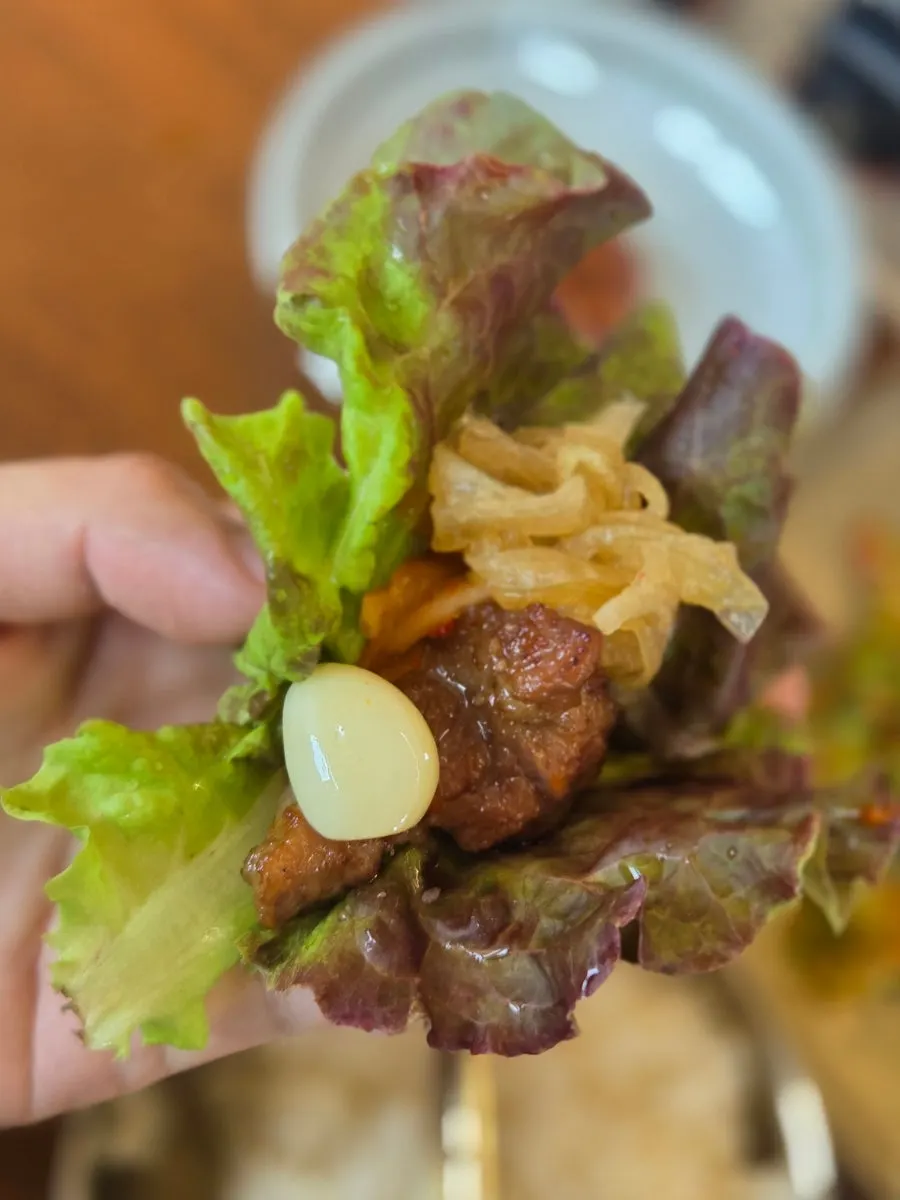 A piece of seasoned pork grill wrapped in lettuce
