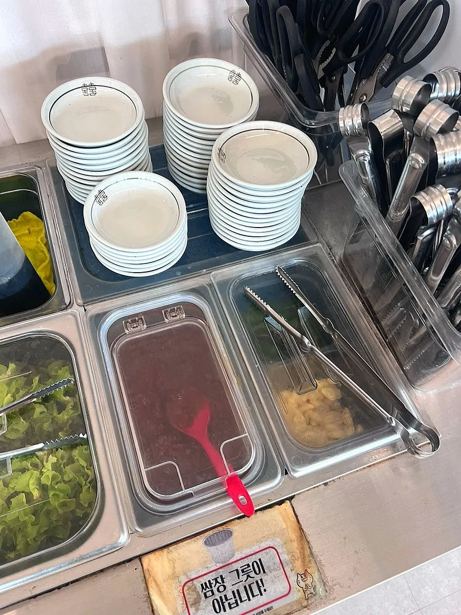 Self-serve bar corner with small plates, scissors, and tongs