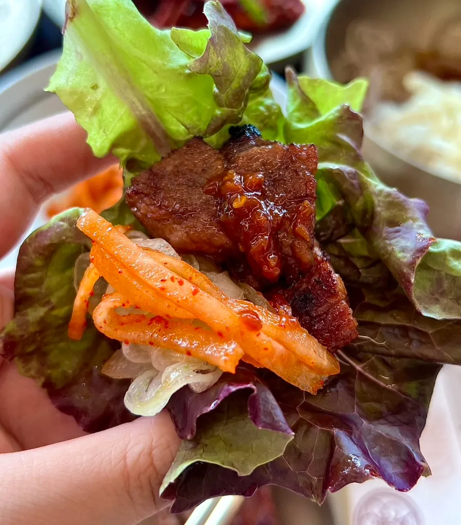 A piece of grilled seasoned galbi picked up with tongs