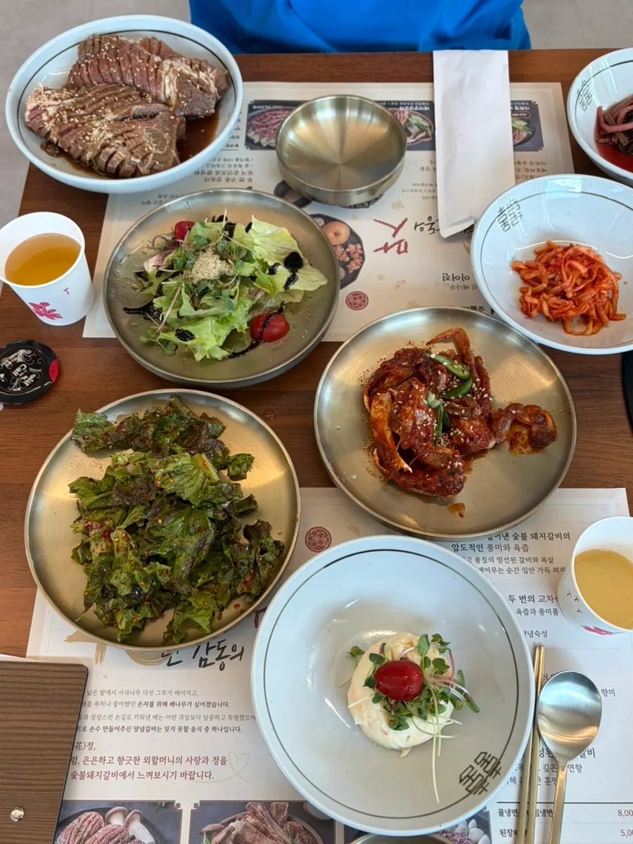 Assorted banchan plates including japchae and potato salad