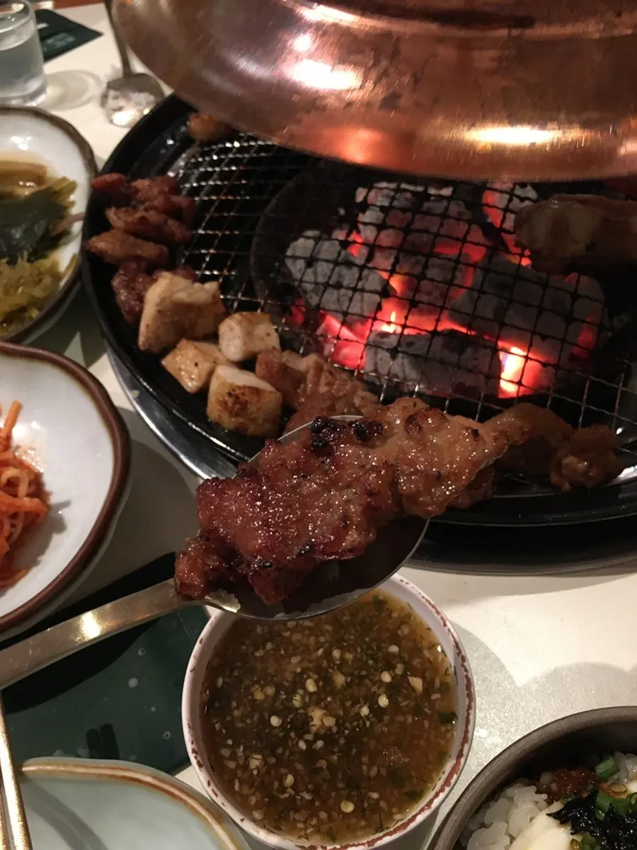 A piece of pork galbi lifted with tongs