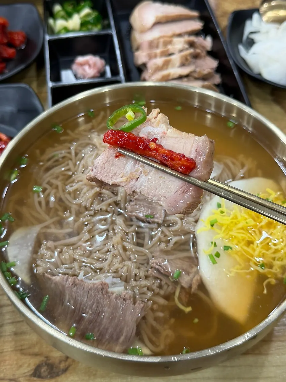 Lifting a bite of pyongyang naengmyeon noodles