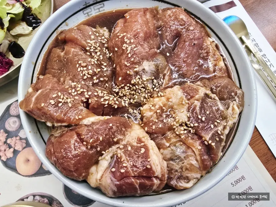 Seasoned pork galbi cooking over the charcoal grill