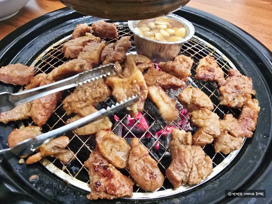 Thick seasoned meat being rolled and flipped on the grill