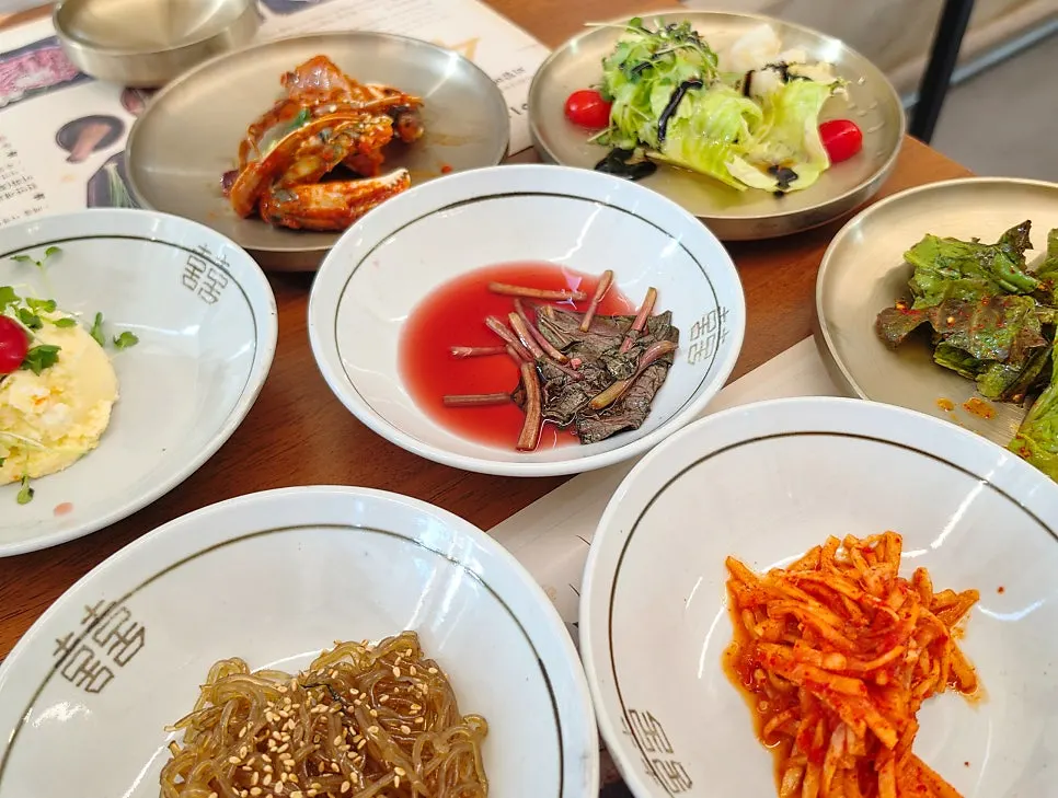 Basic banchan spread with salad, japchae, seasoned crab, and radish salad