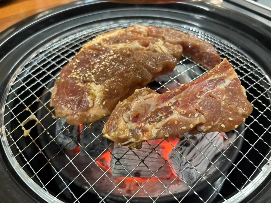 Thick seasoned pork galbi grilling over charcoal