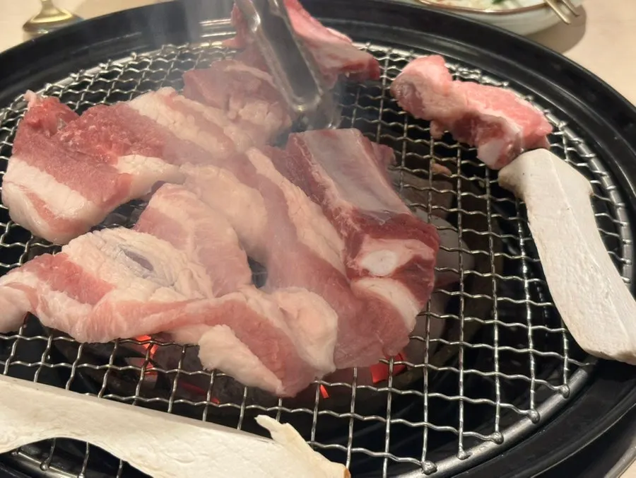 Raw pork galbi cooking on the grill grate