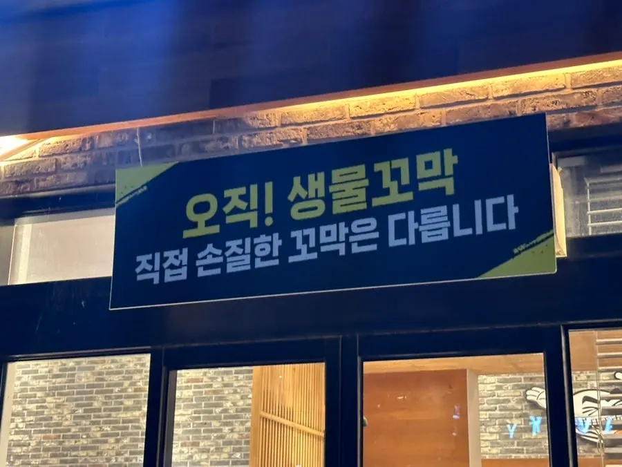 Signage noting that fresh live cockles are prepped in-house