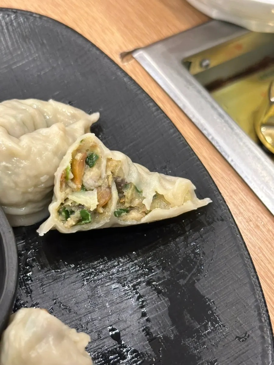 A single cockle dumpling dipped in soy sauce