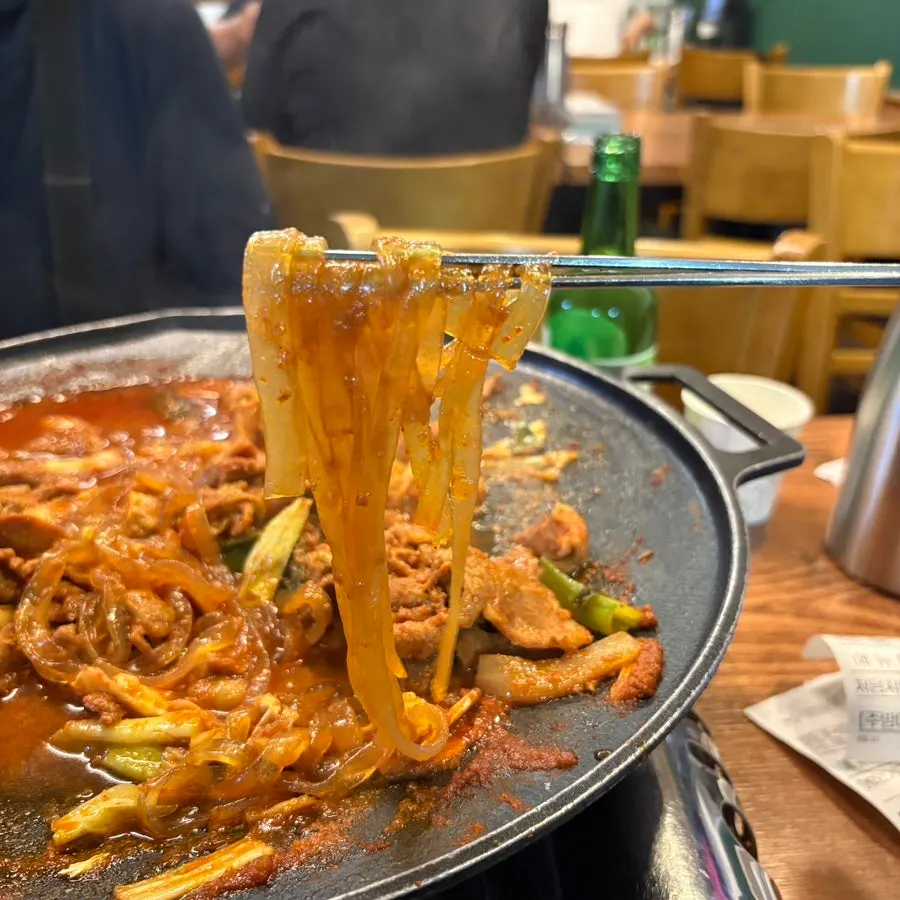 A chopstick-full of sauce-soaked glass noodles