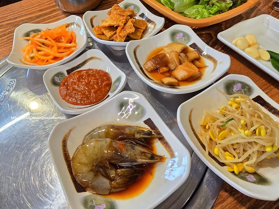 Banchan spread including spicy radish salad and stir-fried fish cake at Pyeongtaek Jumulleok
