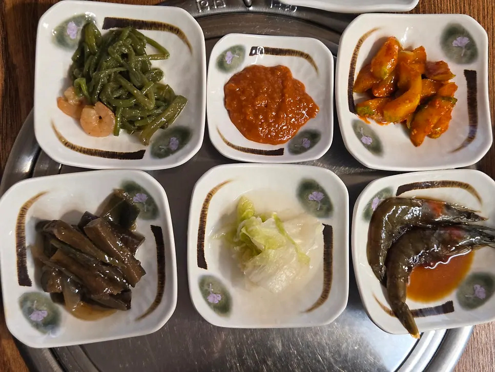 Home-style side dishes including eggplant, white kimchi, and cucumber muchim
