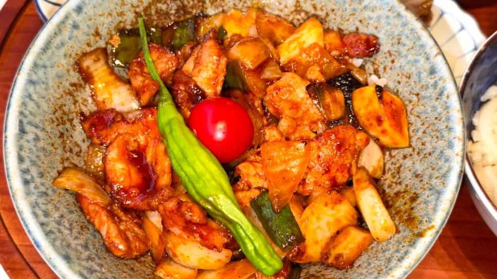 Spicy pork rice bowl topped with peppers and cherry tomatoes