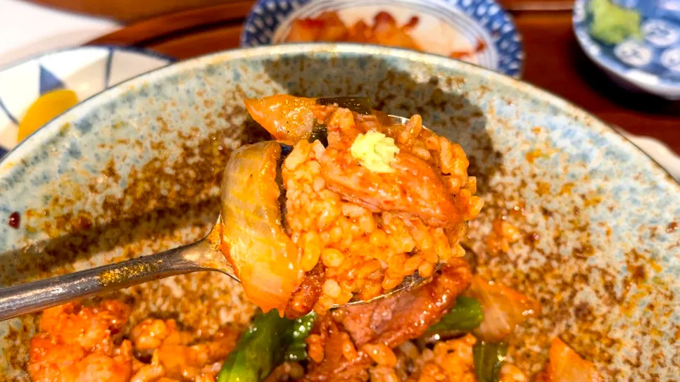A bite of rice and pork lifted together from the bowl