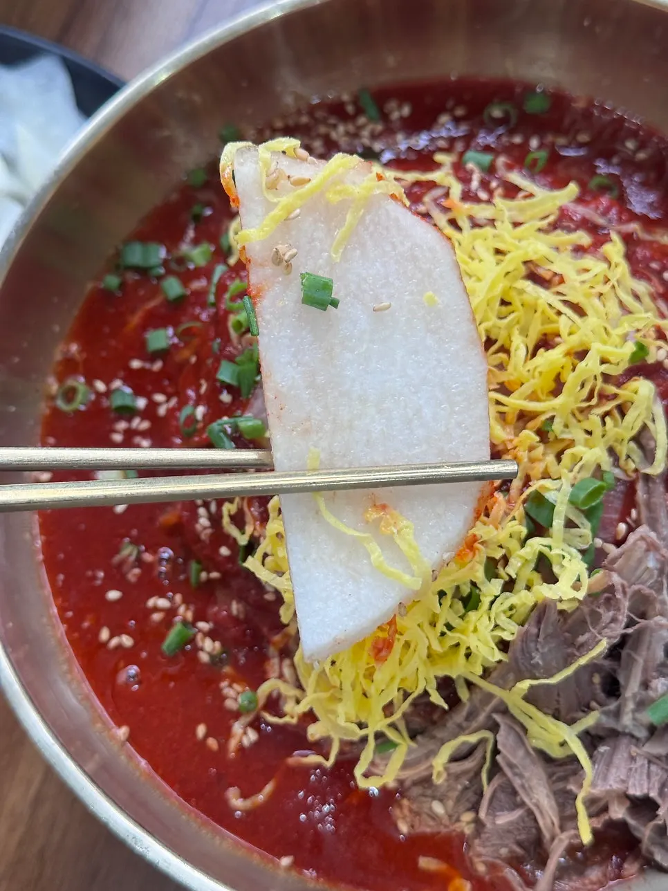 Bibim naengmyeon topped with pear and meat garnish
