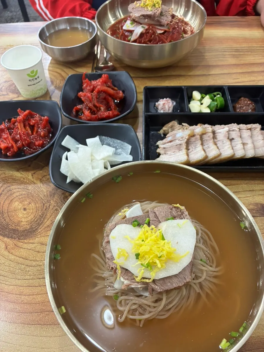A table spread with pyongyang naengmyeon and suyuk together