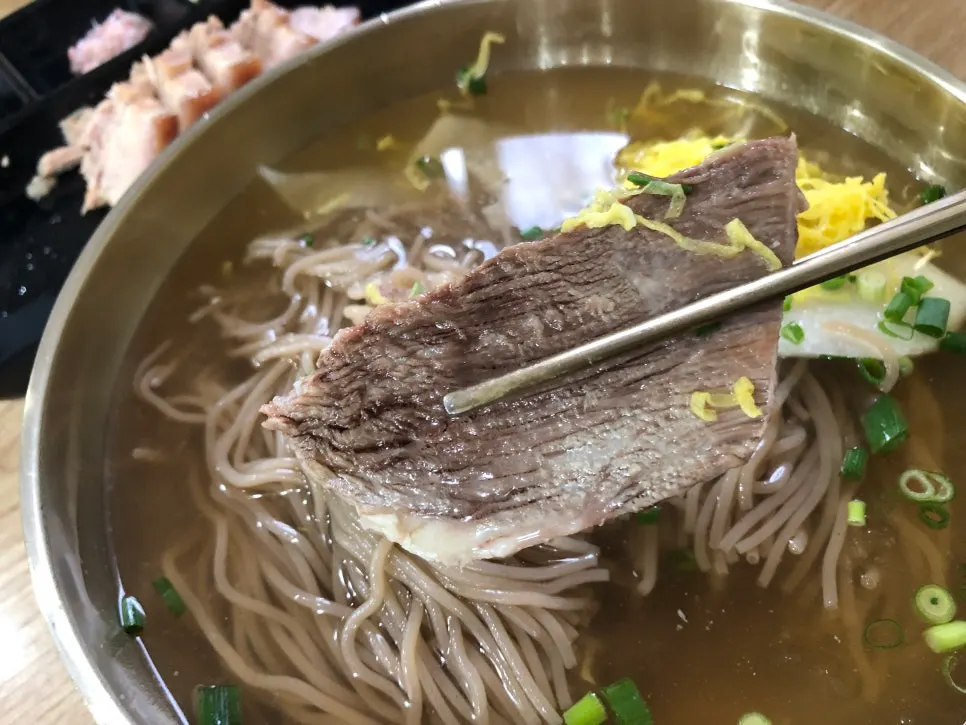 Pyongyang naengmyeon topped with pear, meat garnish, and egg strips
