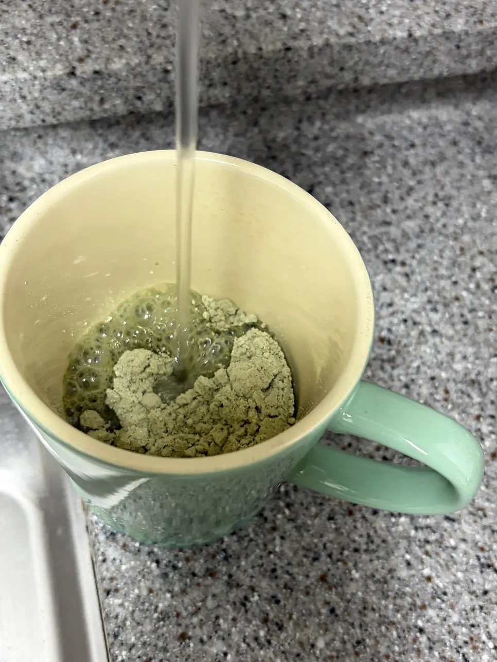 Cold water being poured over the mugwort soy milk powder in a cup