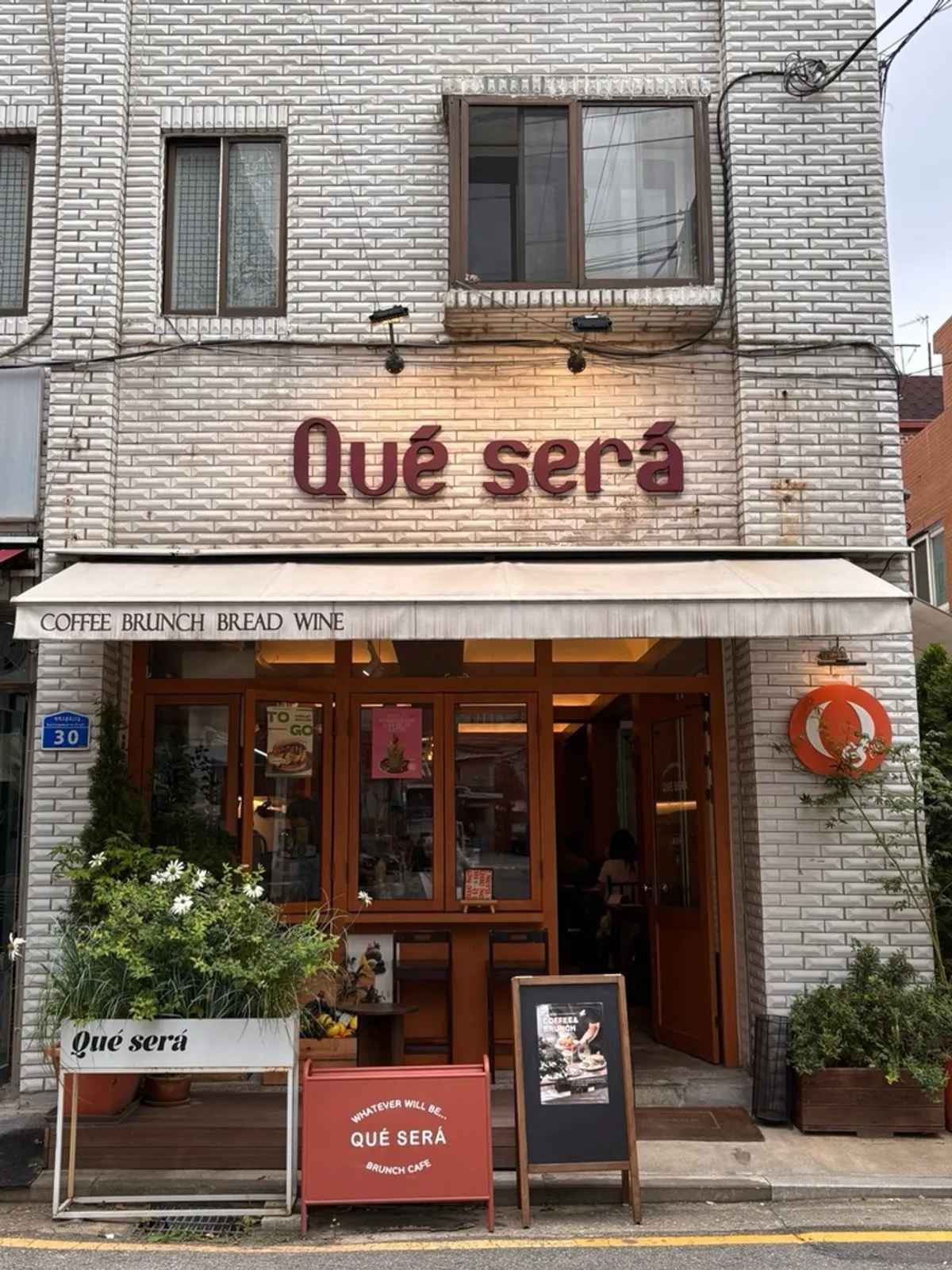 Que Sera's exterior in a cream-colored brick building with the 'Qué será' sign