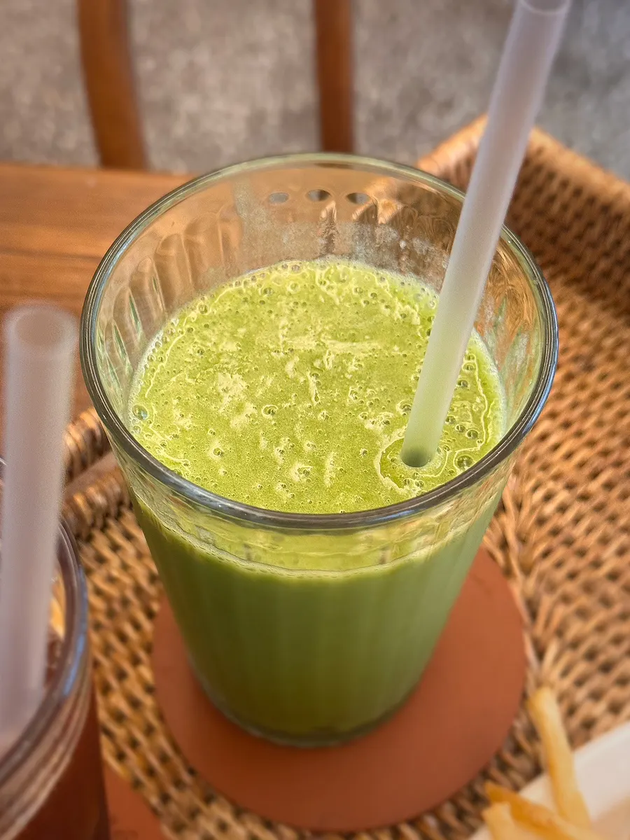Green smoothie placed next to the open sandwich