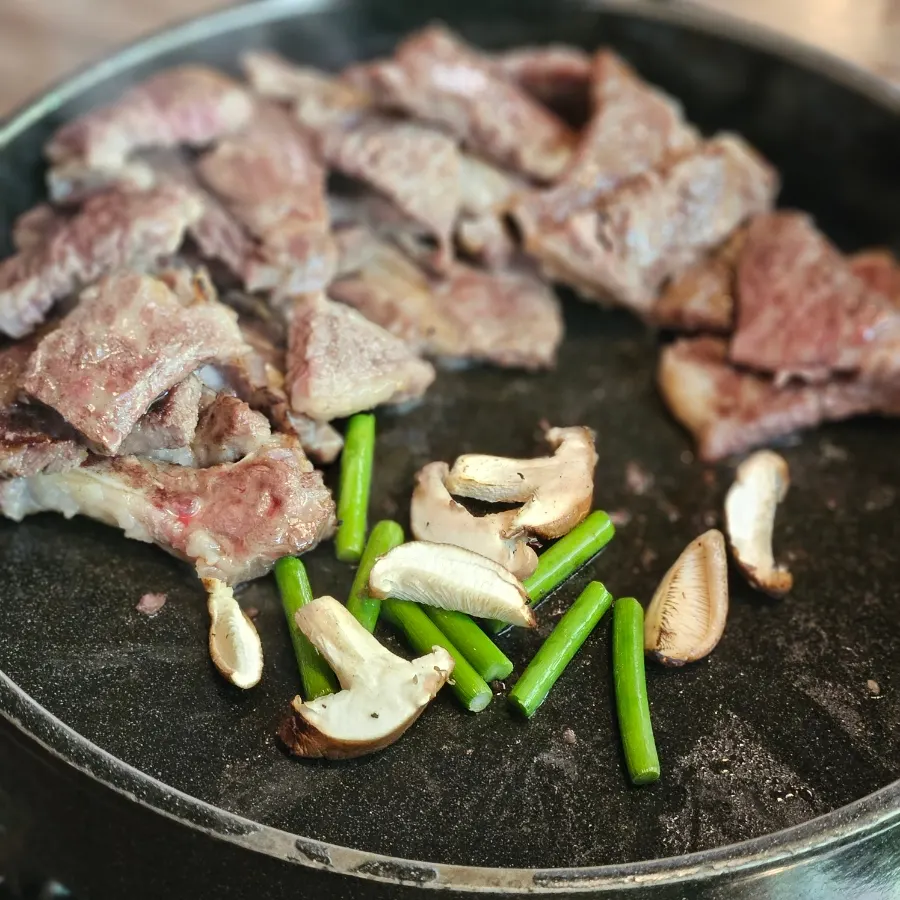 Charcoal-grilled LA galbi with garlic scapes and mushrooms