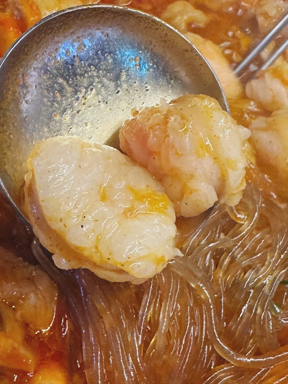 Glass noodles scooped up, soaked in broth
