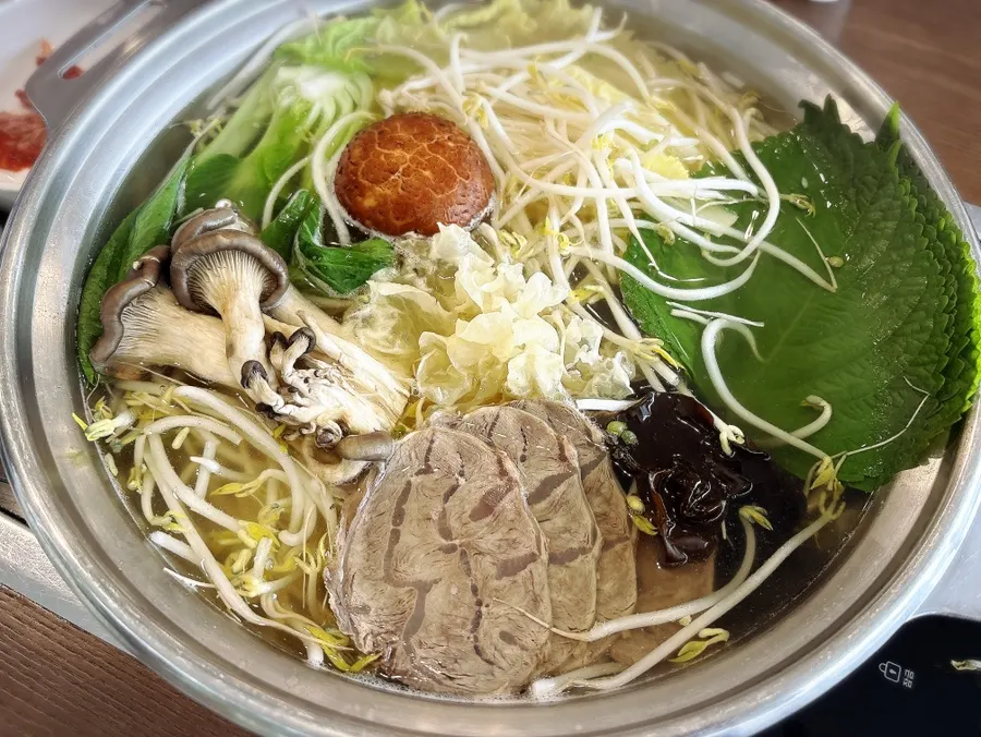 A hot pot piled high with bean sprouts, cabbage, and mushrooms