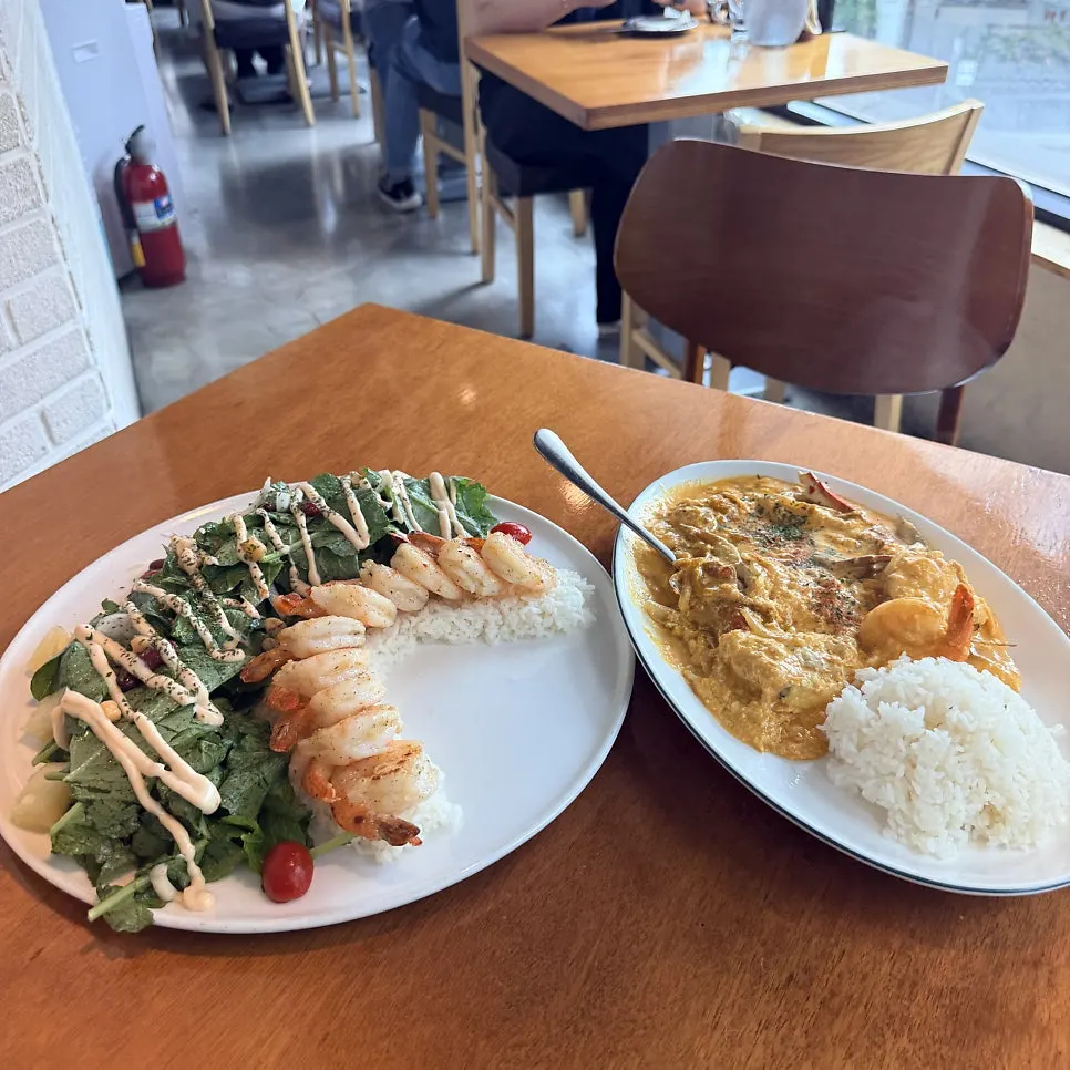 Table set with butter garlic shrimp, pu pad pong curry, and mango lassi
