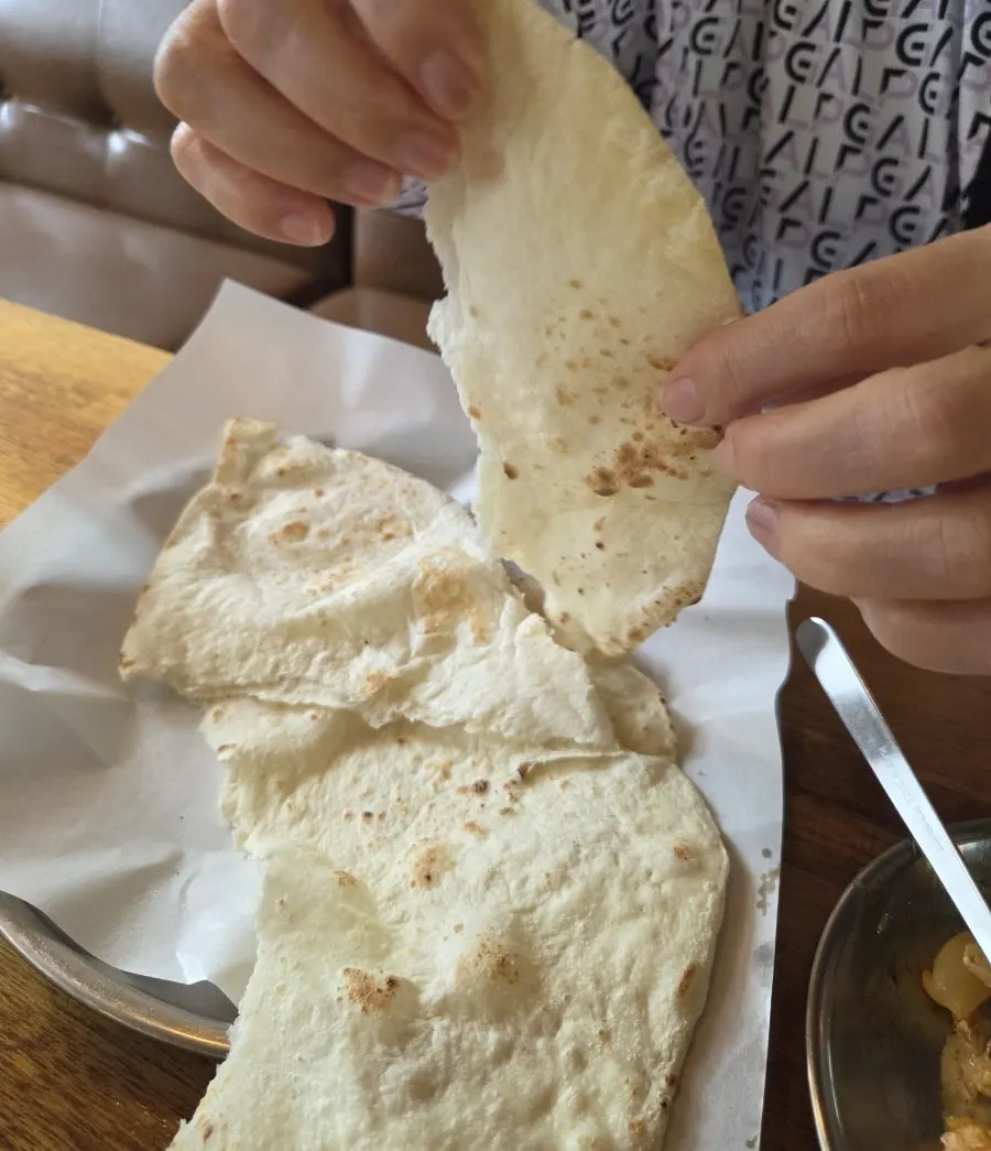 난을 찢어 커리 소스에 찍는 모습