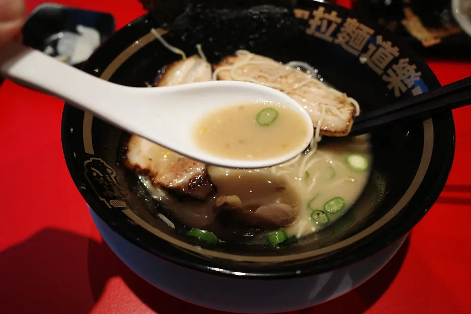 Spooning up the rich ramen broth