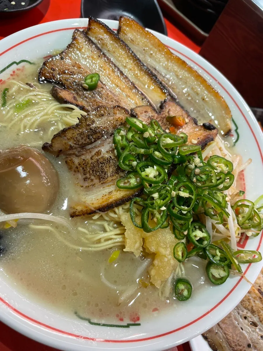 A piece of chashu lifted with chopsticks