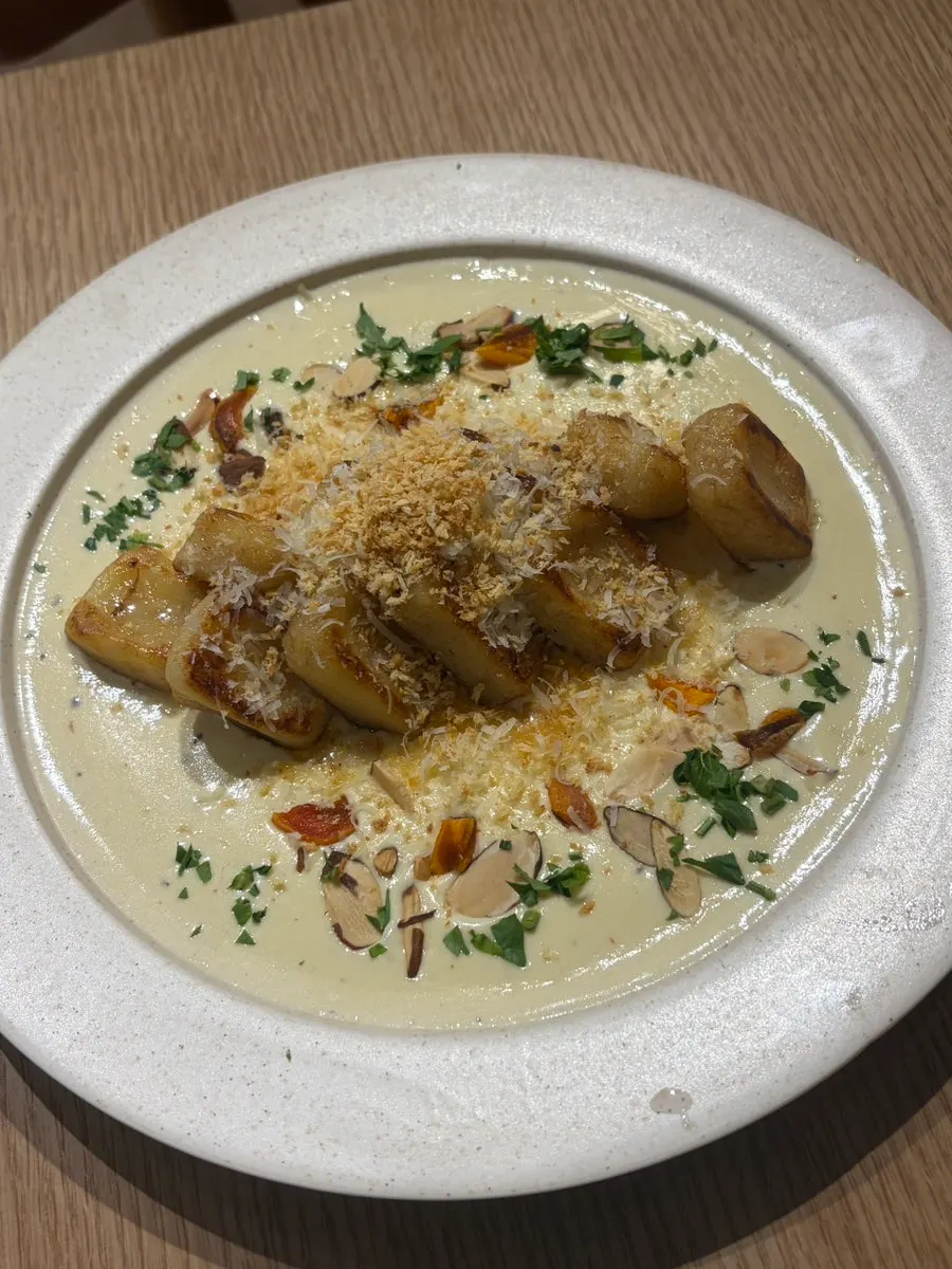 Cream potato gnocchi topped with almonds and cheese powder