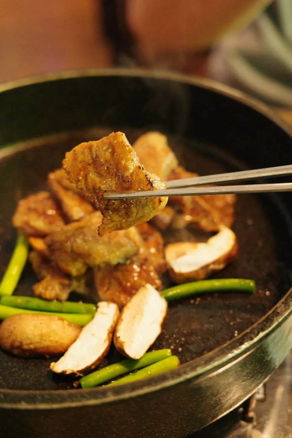 Chopsticks lifting a piece of marinated rib meat