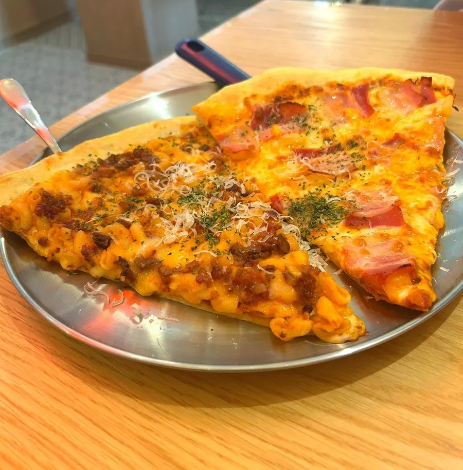 A slice each of bacon Hawaiian pizza and mac and cheese pizza