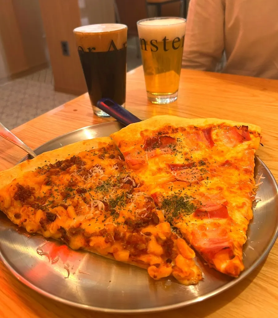 Two glasses of craft beer set beside the pizza
