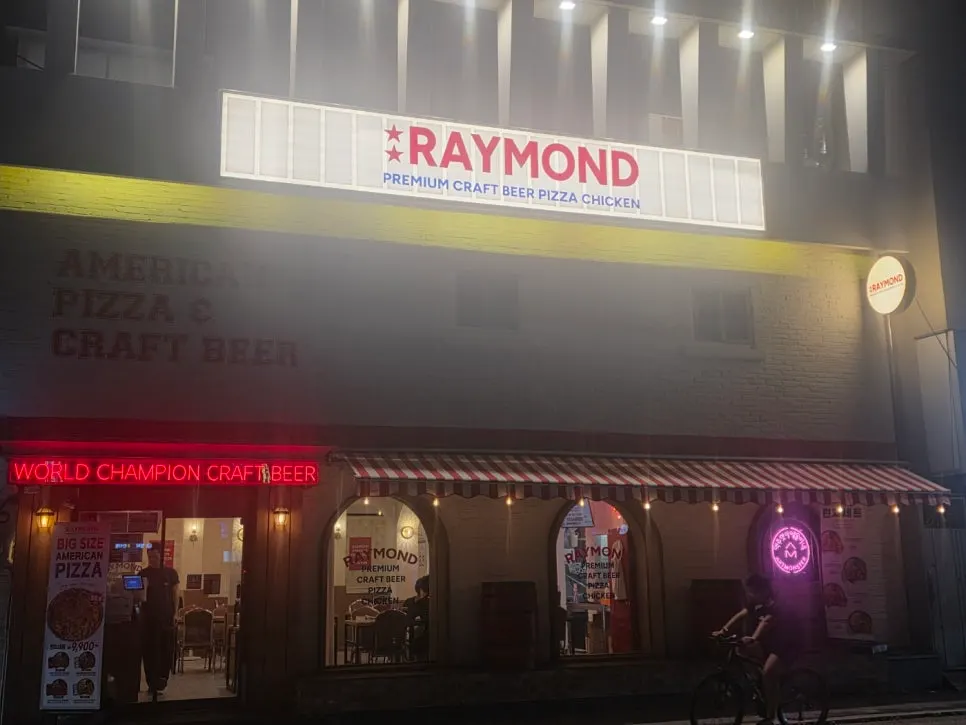 Exterior of Raymond Isu Branch's white standalone building lit up at night