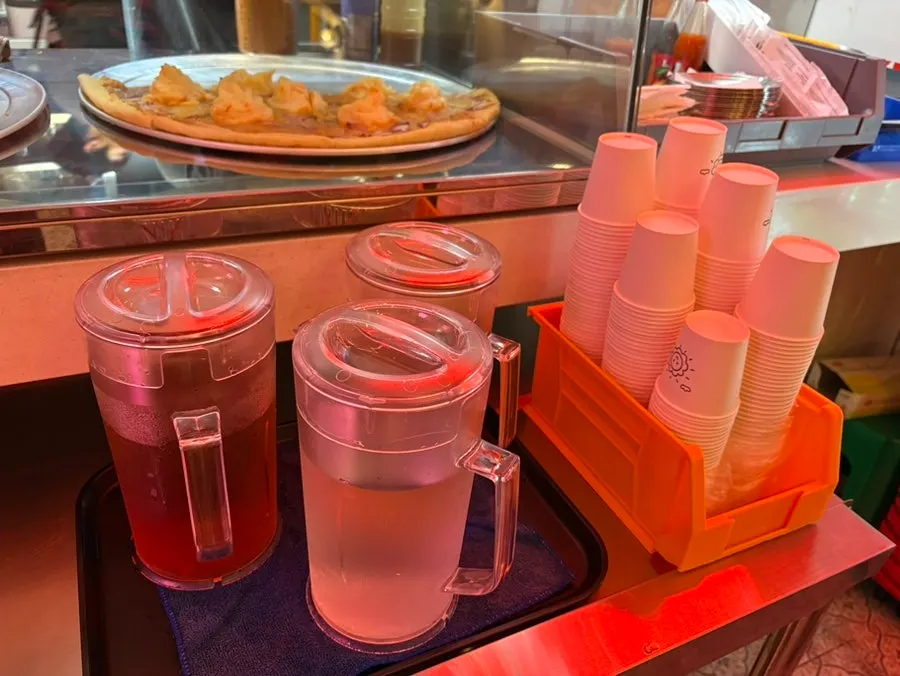 Self-serve bar with crushed pepper, hot sauce, and three types of water
