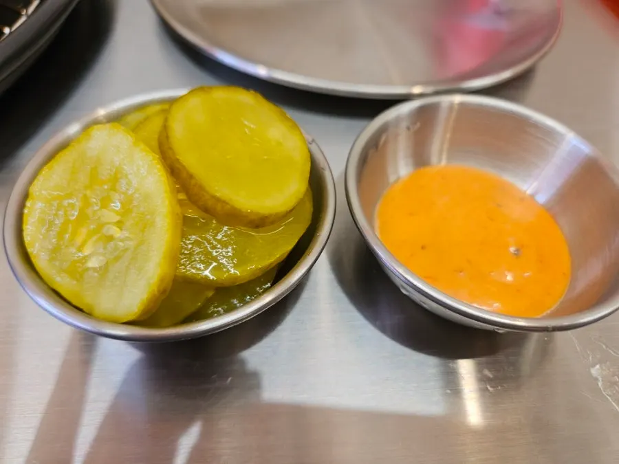 Sauce and pickles served alongside the pizza