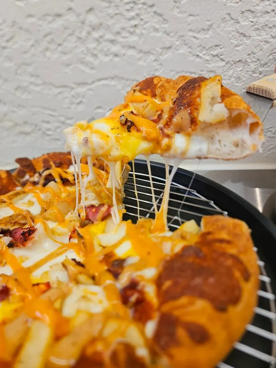 Cross-section of pizza dough topped with potato and bacon