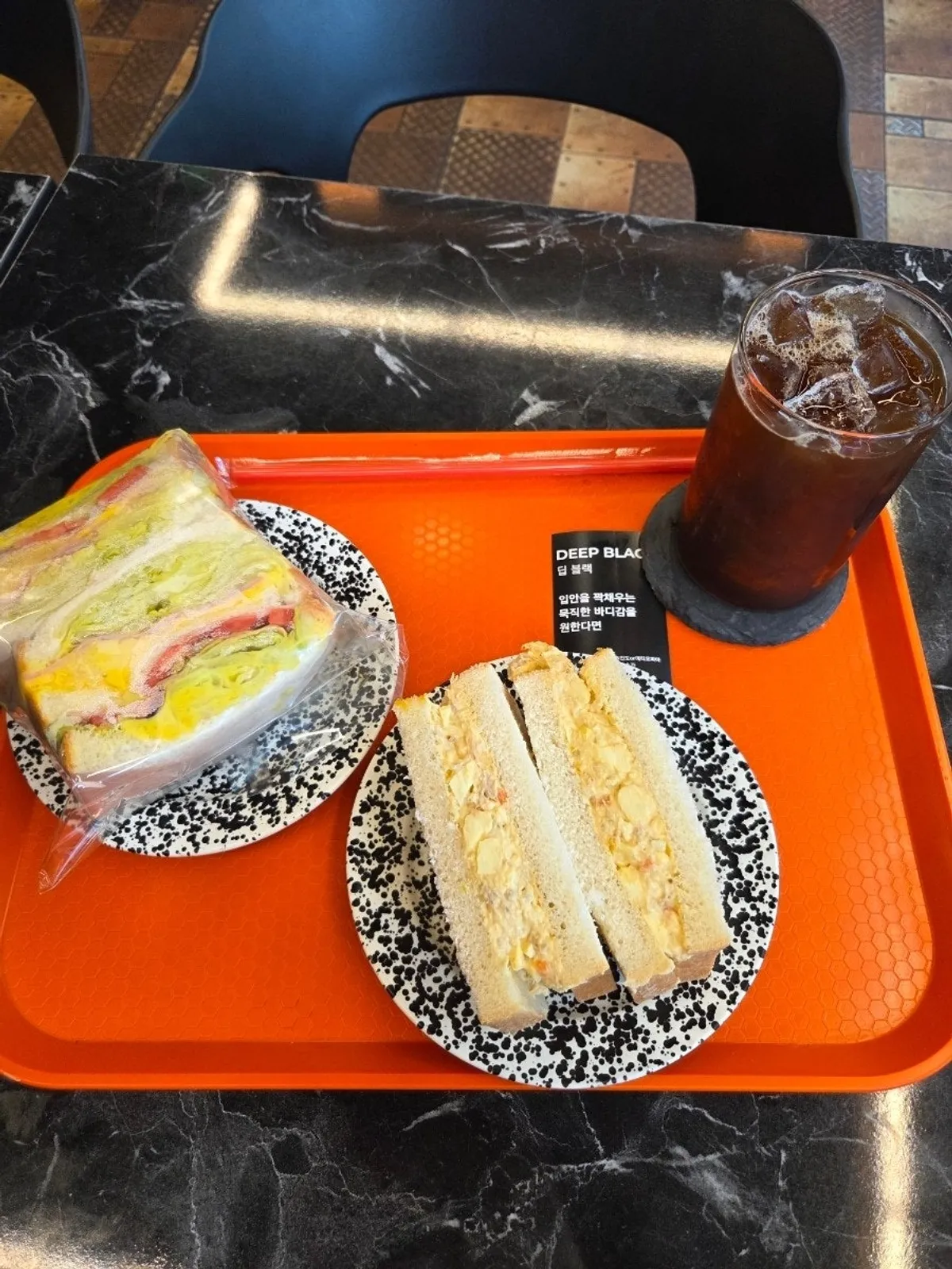 Table spread of club sandwich, tuna-egg sandwich, and iced americano