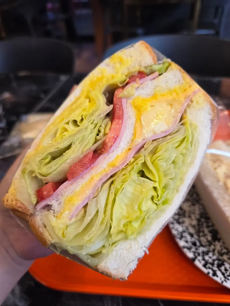 Generously packed club sandwich wrapped in paper